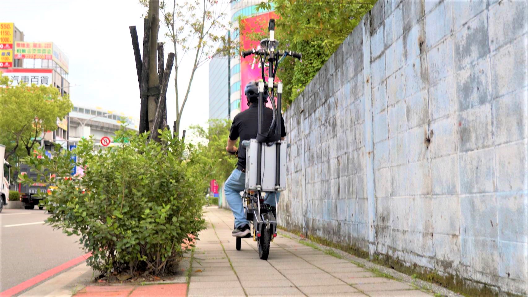 養工處同仁騎乘腳踏車揹負攝影機蒐集影像，將人行道的長度、寬度、鋪面破損程度及固定設施物完成數位建檔、資料檢核。